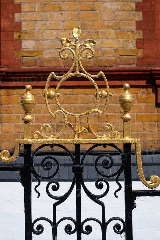 Decorated black and gold painted iron gate in front of a brick wall, Chelsea, London, Great Britain, England, Great Britain