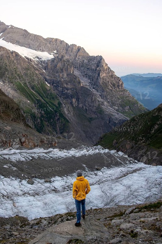 Young man in front of impressive high alpine landscape, at sunrise, Upper Arctic Sea glacier, Bernese Alps, Bernese Oberland, Switzerland