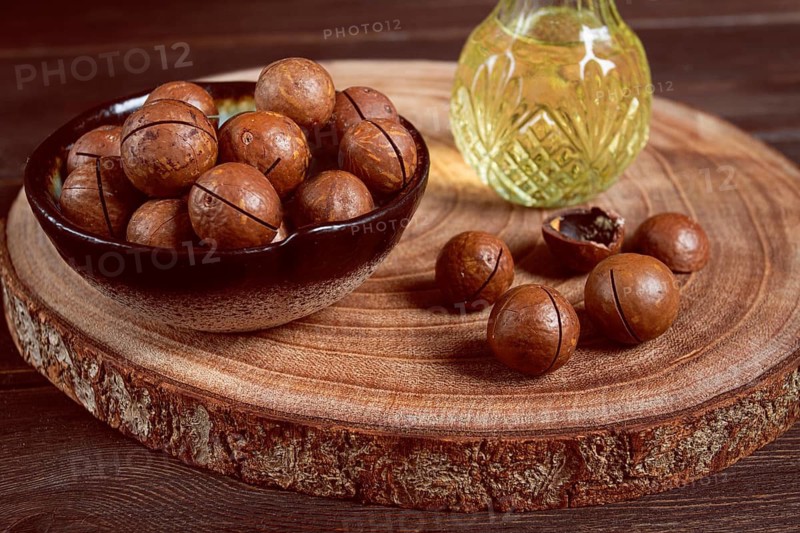 Bottle of macadamia oil, on a wooden board, with macadamia nuts, wooden background, selective focus, no people