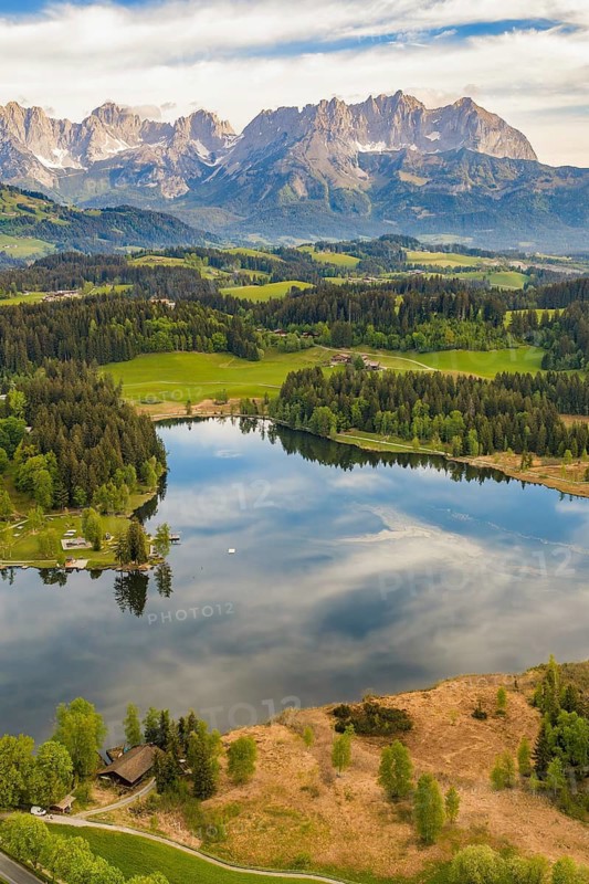 Picturesque mountain lake surrounded by forests and mountains under a blue sky, Schwarzsee circular trail, Kitzbühel, Austria