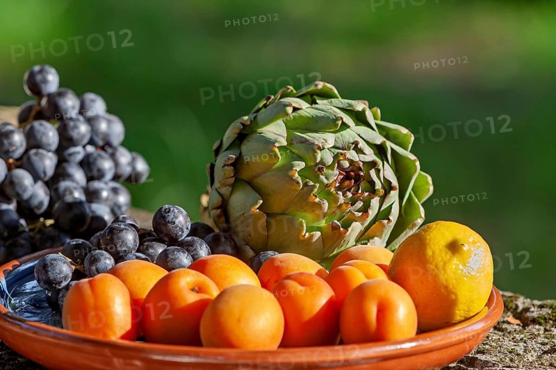 Fruit and vegetable arrangement with apricots, artichokes and grapes outdoors, Provence, France