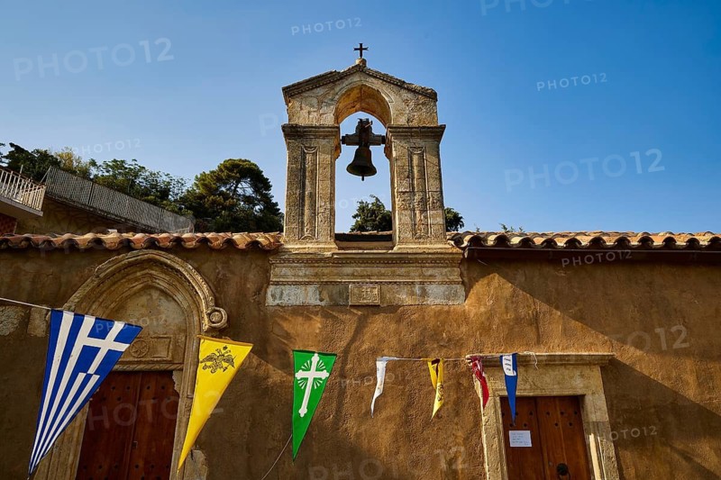 Small bell tower with colorful flags against a clear sky, Meronas village, Meronas, Amari Basin, Central Crete, Greek Islands, Greece