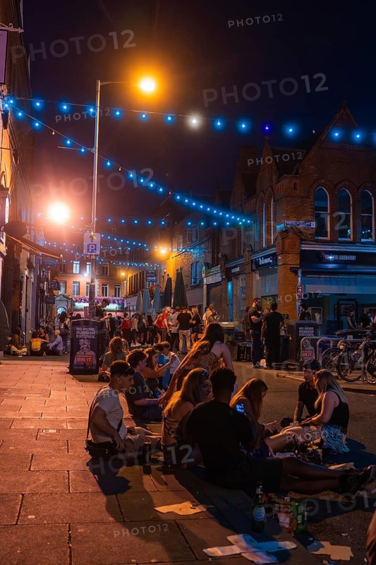 Group of people sitting on a street surrounded by warm lights and lanterns, nightlife, Dublin, Ireland