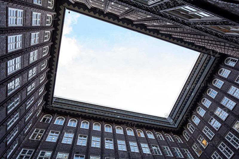 11.6.2018: Low angle perspective of the inner courtyard of the Chilehaus in the Kontorhaus district. The dark brick expressionist architecture features many windows and a sharp, triangular sky view. Hamburg, Germany