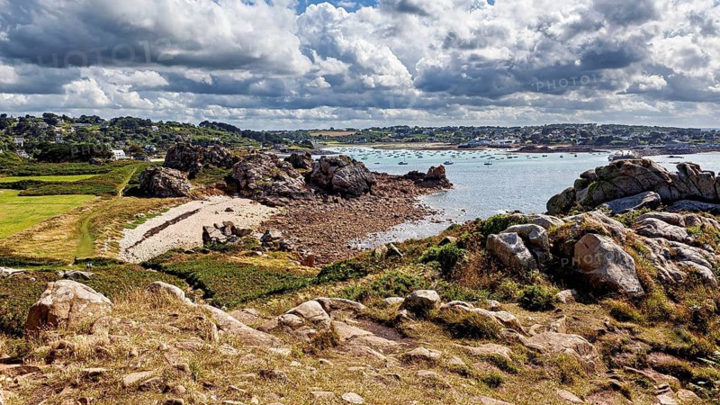 Rocky coastal landscape with beach and blue sea under a cloudy sky, The coastal landscape near Cleder in Brittany