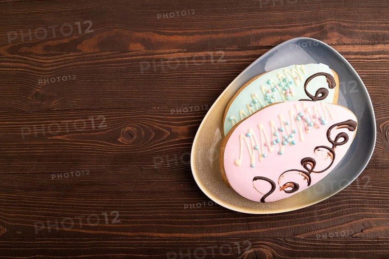 Glazed pink and blue decorated cookies, on brown wooden background, copy space, top view, flat lay