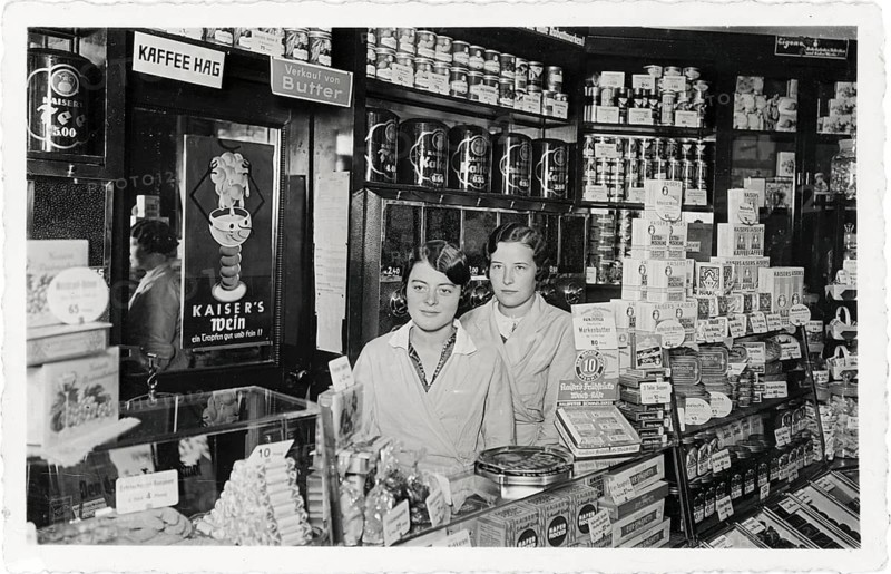 Colonial goods, retail, sales counter, shop, business, profession, twenties, saleswoman, coffee shop, two woman in a shop surrounded by shelves full of goods and vintage advertising, around 1922