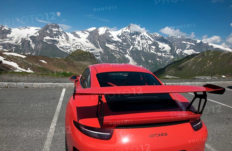 Red Porsche GT3 RS sports car in the Grossglockner High Alpine Road parking lot in front of Mittertörl, in the background Grossglockner Massif Mountain Range, Grossglockner High Alpine Road, Fusch, Salzburg Province, Austria