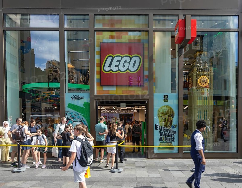 People in line queuing outside flagship Lego store shop, Swiss Court, Leicester Square, London, England, UK - the largest LEGO store in the world