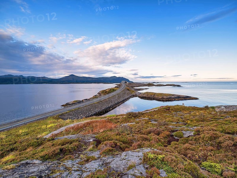 A long bridge stretches across a quiet coastline under a blue sky, Storseisundbrua bridge, part of the Atlantic Road, Atlanterhavsveien, Møre og Romsdal, Norway