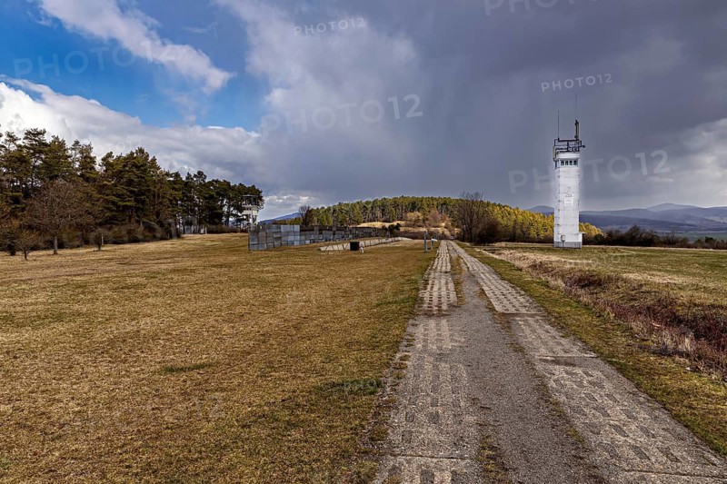 A long way leads to a white watchtower in a meadow with hills in the background, the Point Alpha memorial between Rasdorf and Geisa in the Rhön