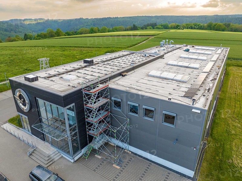 Industrial building with adjacent scaffolding, embedded in a hilly landscape, PV assembly, Perrot company, Calw, Germany