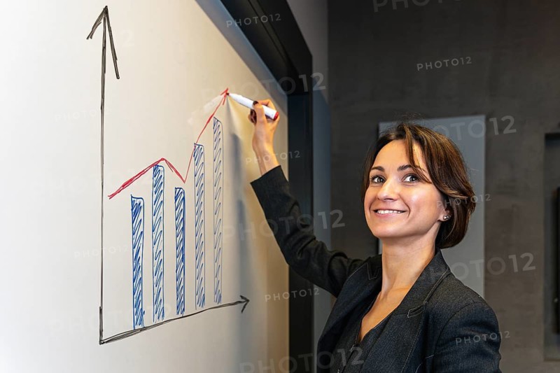 Smiling Businesswoman Drawing Growth Chart on Whiteboard in Office
