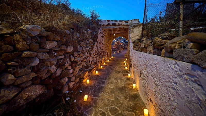 Open-air cinema, a well-lit stone path at night flanked by stone walls and lanterns, Kastro, old castle above Chorio, Kimolos, Cyclades, Greek Islands, Greece