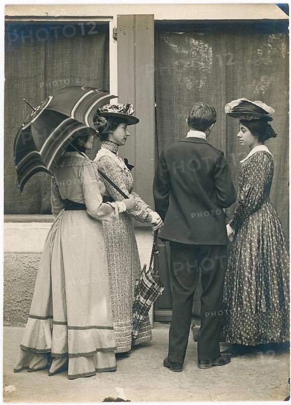 Elegant ladies, parasol, turn of the century, hats, conversation, historical photo of three woman and a man in old-fashioned clothing with umbrellas, around 1905