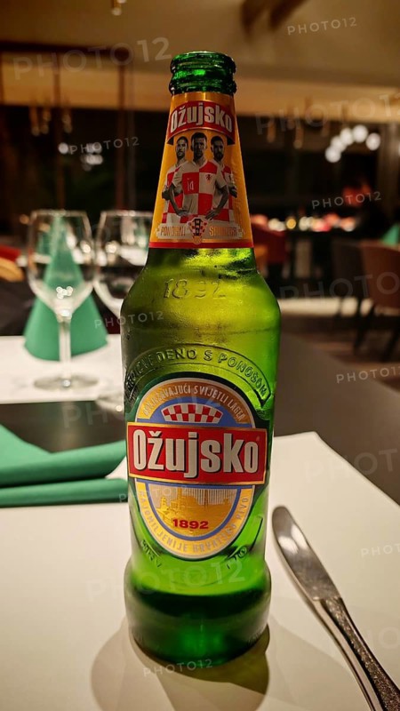 An Ožujsko beer bottle is on a table in a finely decorated restaurant, Croatia