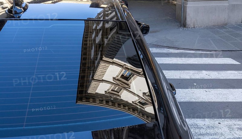 Reflection of a residential building in the rear window of a parked car, Florence, Italy