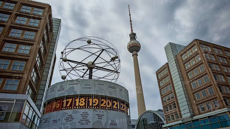 View of the World Clock and the Berlin TV Tower with surrounding buildings on a cloudy day, Alexanderplatz, Berlin