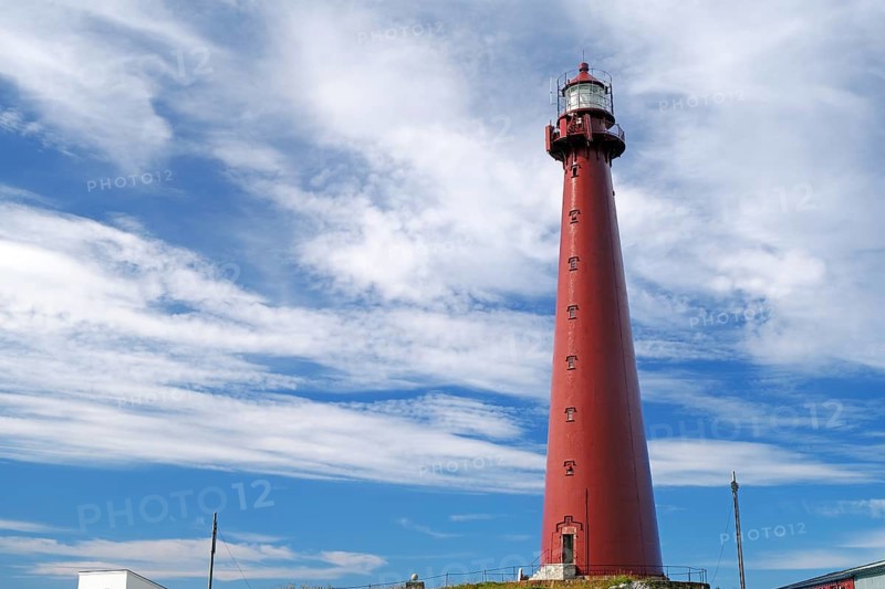 A tall red lighthouse with clouds in the sky in a coastal landscape, landmark, Andenes, Andøya, Nordland, Norway