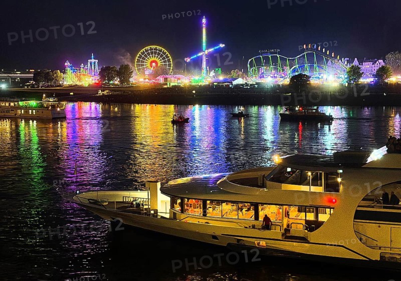 Rheinkirmes, largest funfair on the Rhine with rides, view across the river with boat at night, Düsseldorf, North Rhine-Westphalia, Germany