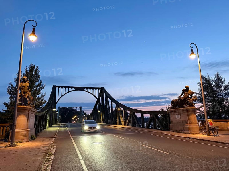 The Glienicke Bridge, also known as Agent's Bridge in GDR times and is world-famous, as captured secret agents were regularly exchanged here between West and East. Back then, the border between West Berlin and the GDR ran right in the middle of the bridge. The steel bridge spans the Havel and connects the Berlin district of Wannsee with the state capital of Brandenburg, Potsdam. Night shot. Since November 10, 1989, one day after the fall of the Wall, the border crossing has been reopened to all people. Königstraße/Berliner Strasse, Berlin, Potsdam, Brandenburg, Germany
