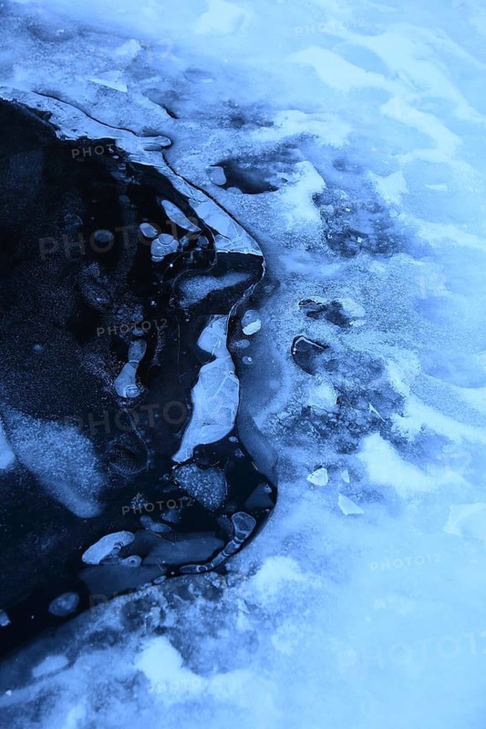 Frozen surface structure with visible cracks and glacier ice, air bubbles trapped in the ice of a frozen lake in winter, Pragser Wildsee, South Tyrol
