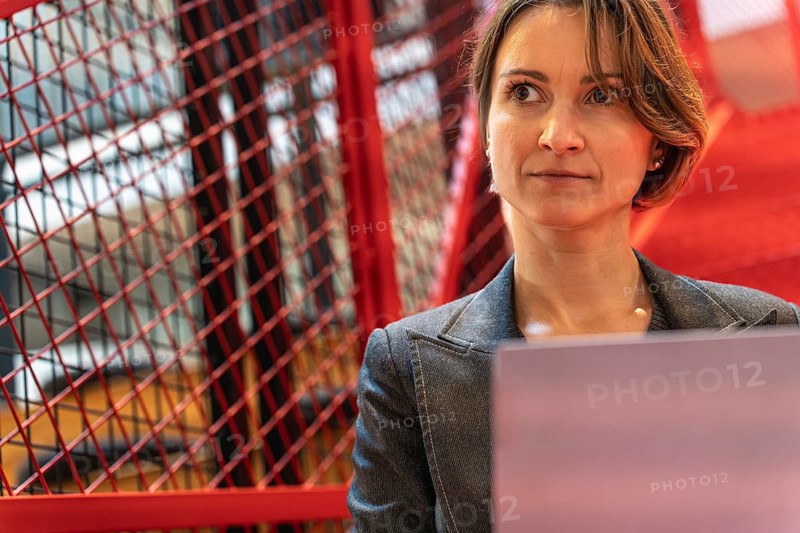 Thoughtful businesswoman close-up with laptop against red blurred background, copy space
