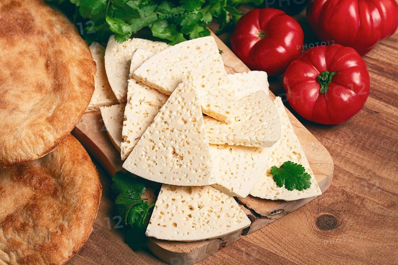 Georgian sliced cheese, on a wooden chopping board, with tomatoes with herbs and lavash, rustic style, Georgian cuisine, no people