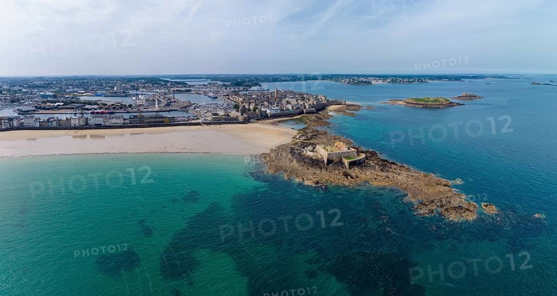 Aerial view, panorama of the historic Fort National island fort on the sandy beach of Saint Malo at low tide. Behind it is the distinctive city wall, Les Remparts, which encloses the old town center of the corsair town. Côte d'Émeraude, Emerald Coast, Ille-et-Vilaine Department, Brittany, English Channel, France
