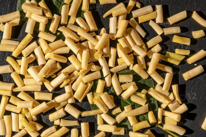 Yellow bean pieces scattered on leaves, illuminated by sunlight