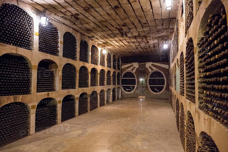 Wine cellar with bottles on stone shelves, illuminated by lamps, arranged and historic, wine cellar, Milestii Mici Winery, Mile?tii Mici, Republic of Moldova, Moldova