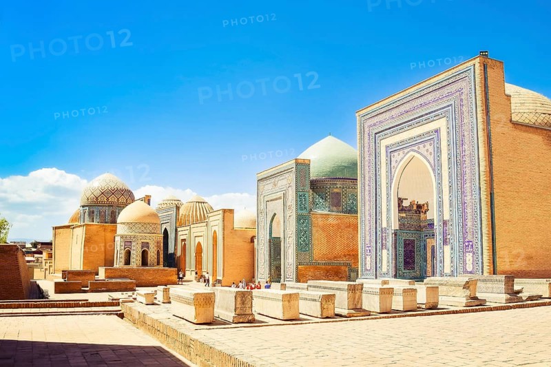 Cinematic Shah i Zinda necropolis in Samarkand. Visitors explore the stunning blue-tiled mausoleums and turquoise domes of historic UNESCO Silk Road landmark