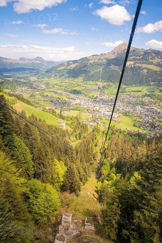 View from a cable car of a green wooded valley and mountains under a blue sky, Hahnenkamm, Kitzbühel, Austria