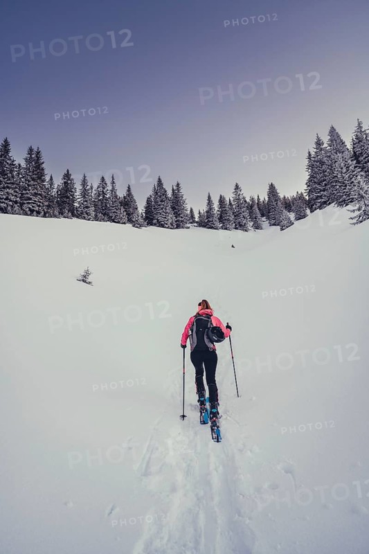 A woman's ski tour at sunrise on the Tegelberg in the Allgäu in the Ammergebirge, Bavaria, Germany