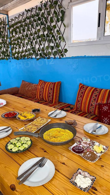 Spread of moroccan breakfast dishes. Including omelette. Flatbread. Olives. Cucumber. Jam. And butter