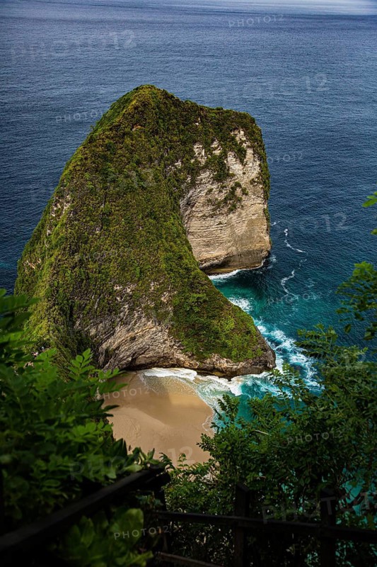 View of a cliff, surrounded by lush vegetation and the wild sea, on a sandy beach, a bird's-eye view of the famous, deserted white sandy beach of Kelingking (T Rex Beach), Nusa Penida Island, Klungkung Regency, Bali, Indonesia, South-East Asia