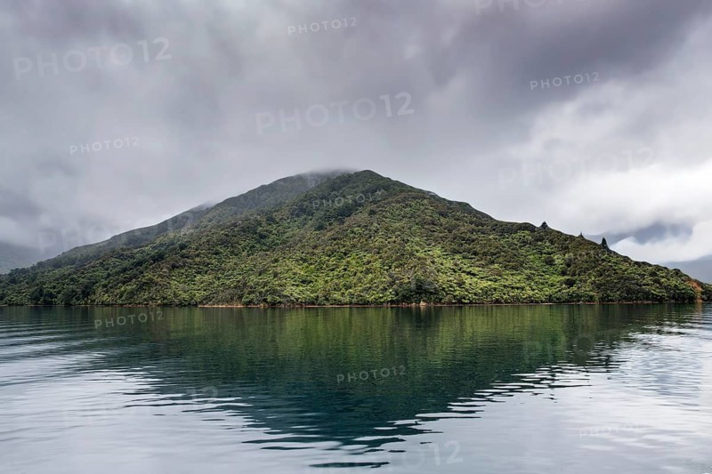 Misty mountain reflected in the calm waters of the Marlborough Sounds, New Zealand