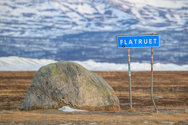 A road sign with the name Flatruet next to a large stone in a snow-covered landscape, Flatruet, Berg, Härjedalen Län, Sweden
