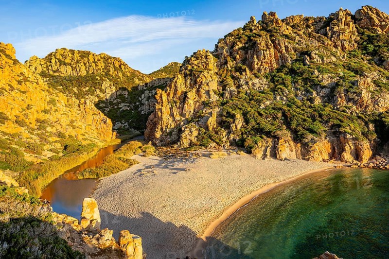 Landscape of the coastline with a sandy beach and blue water at Costa Paradiso on a sunny day at evening, Sardinia, Italy