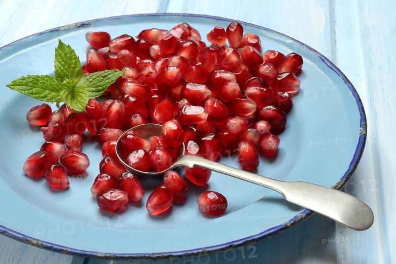 Pomegranate seeds and spoons on plate, Punica granatum