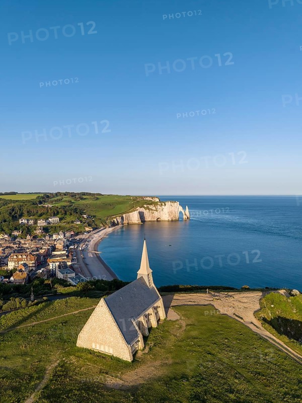 Aerial view of the Notre Dame de la Garde chapel after sunrise at the Falaise d'Amont viewpoint, on the right the coastal town of Étretat with the beach, on the horizon the Porte d'Aval rock formation, Étretat, Alabaster Coast, La Côte d'Albâtre, chalk cliffs, English Channel, Seine-Maritime, Normandy, France
