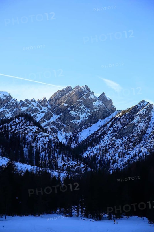 Snowy mountain landscape with forests in the foreground under a clear blue sky, Pragser Wildsee, Lago di Lake Prags, frozen mountain lake in winter, Prags, Lake Prags, South Tyrol, Italy