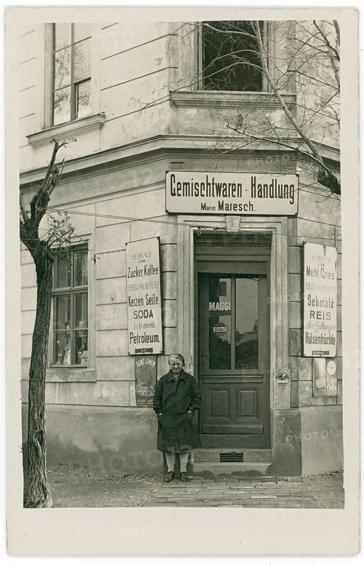 Vienna, shop, general store, Vienna 21, Floridsdorf, Klagergasse 2, poverty, black and white photo of a woman in front of an old shop on a alleyway corner, around 1914