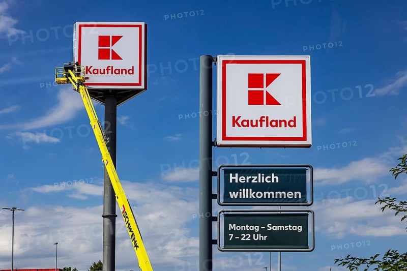 Advertising pylon at the Kaufland supermarket. Workers are renewing the logo by means of a climber. Zimmern ob Rottweil, Baden-Württemberg, Germany
