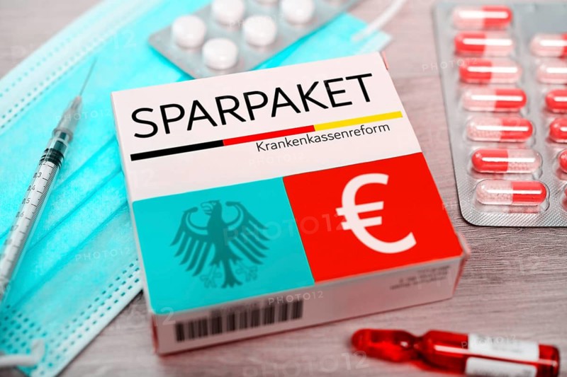 PHOTO MONTAGE, pill box with inscription savings package, symbolic photo health insurance reform +++ editorial use only