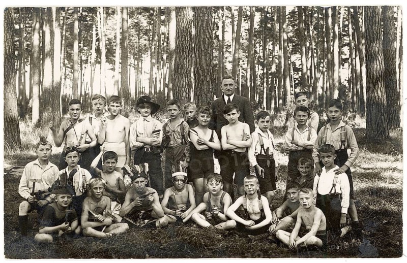 Trip, school class, pine forest, teacher, boy class, boys, twenties, large group of boys with an adult posing in the forest. Some boys are shirtless. Black and white, around 1924