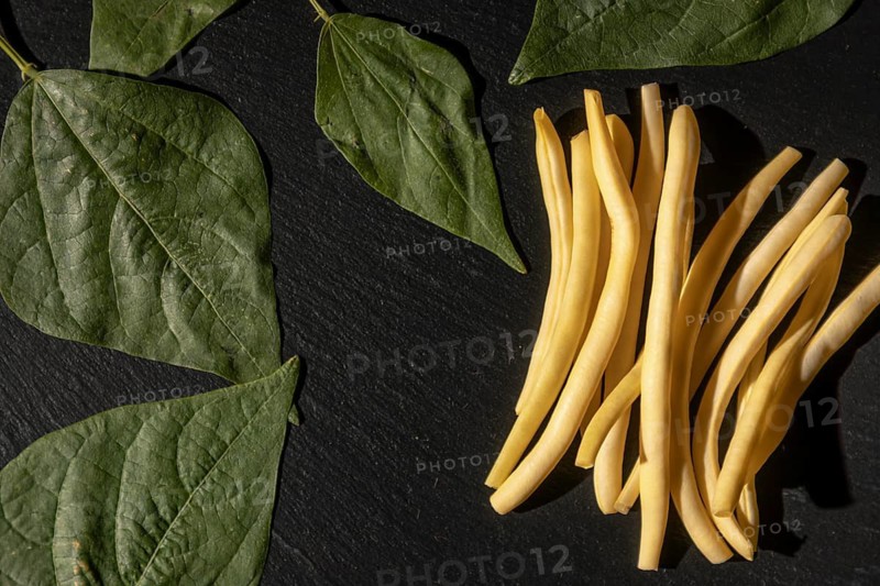 Yellow beans combined with green leaves on a black background