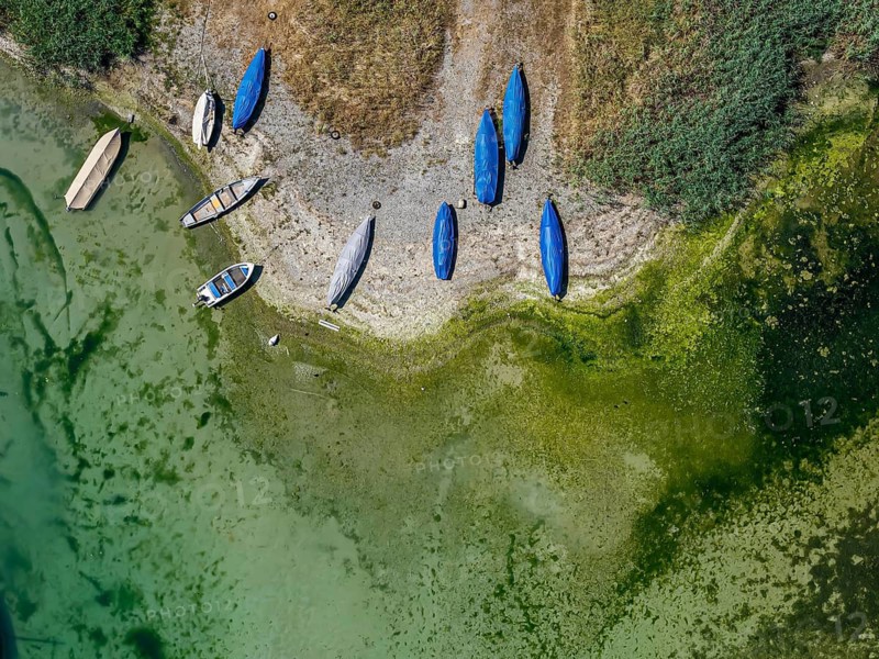 Lake Constance shore on the island of Reichenau with boats and swimmers. The bottom of the lake can be seen in many shallow water zones. The water level of Lake Constance is currently low for the time of year. Reichenau, Baden-Württemberg, Germany