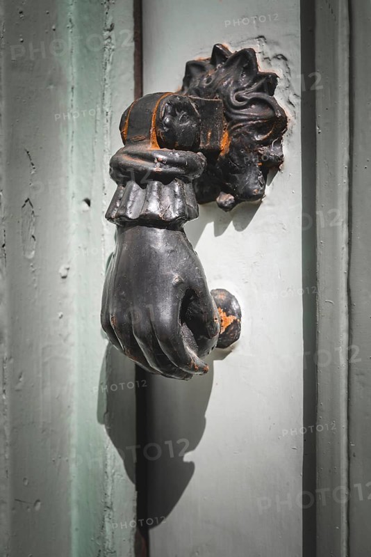 Old French door knocker with hand on a front door in France