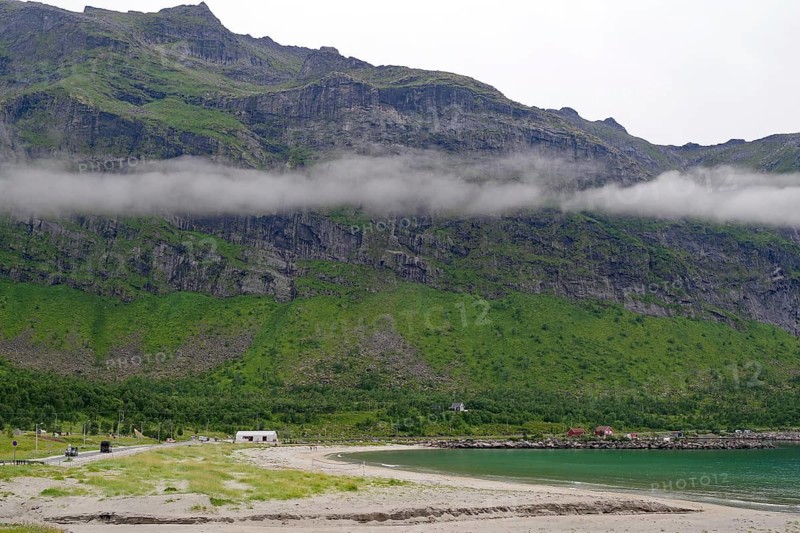A misty coast with sandy beaches and mountains in the background. Clouds hang low over the landscape, Ersfjord, Mefjordvaer, Senja, Troms, Norway